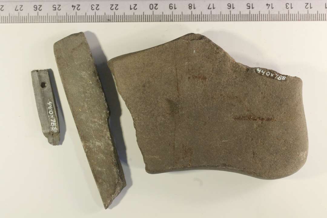 Tre fragmenter af hvæssesten. 1 stk.: 11x8 cm. af sandsten?, 1 stk.: 9x2 cm., 1 stk-. 4x0,9 cm., den mindste med ophængningshul. De to mindste af lysegrå skifer