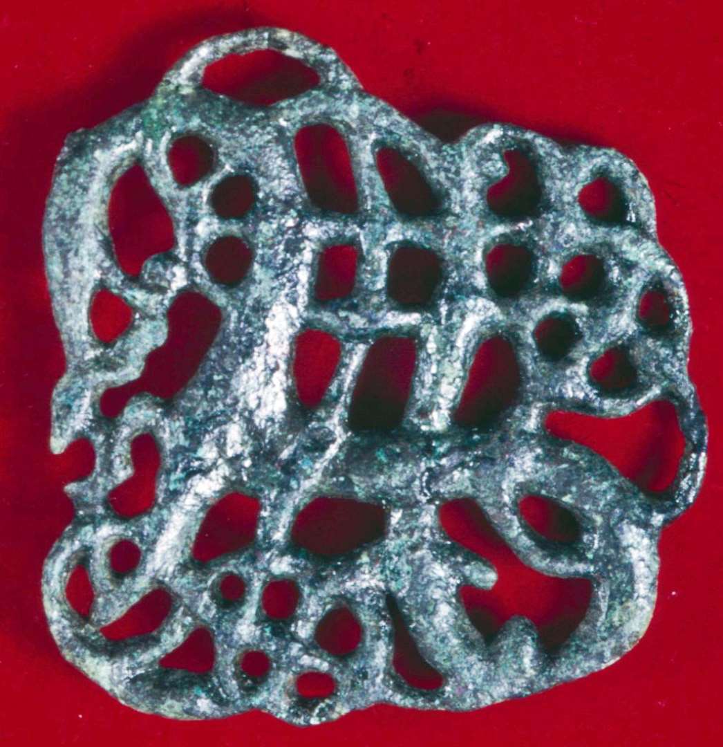 Komplet og flot Urnesfibel, ca. 4,5 x 4,5 cm. Nålefæstet med enden af jernnål tilstede,  den anden del af nåleanordningen er knækket af.