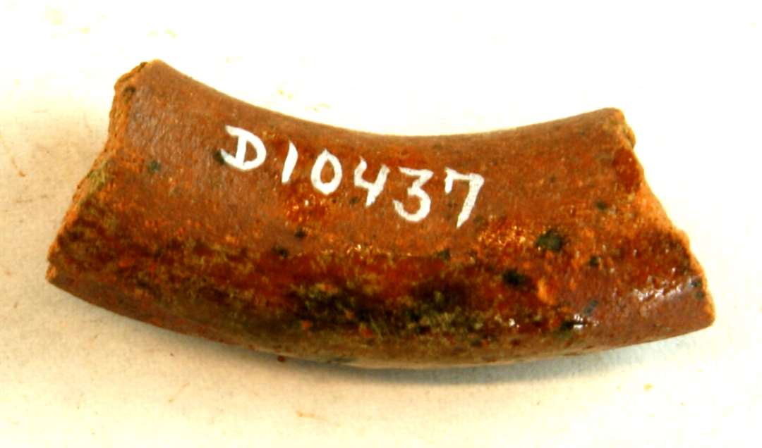 1 fragment af pølseformet hank af rødbrændt lergods med plettet grønligspættet, klar blyglasur. Gruppe 1. Flamsk