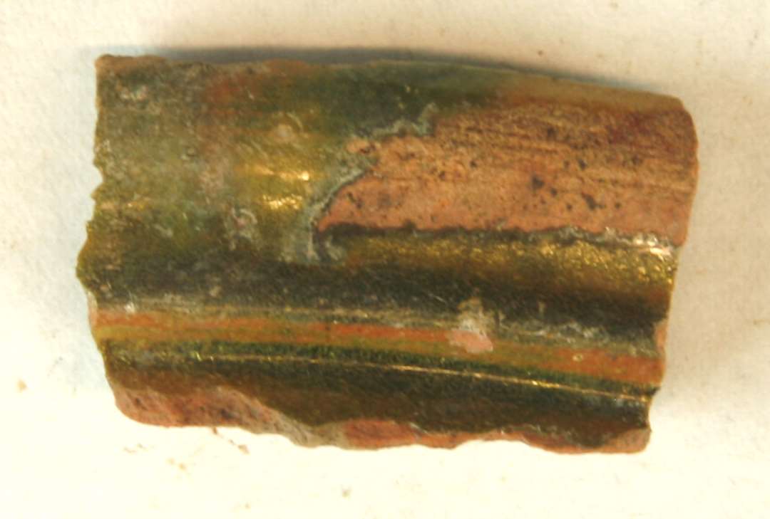 1 randskpår fra rødbrændt kande med profileret rand og klar til grønlig blyglasur. Gr. 1. Sands. flamsk