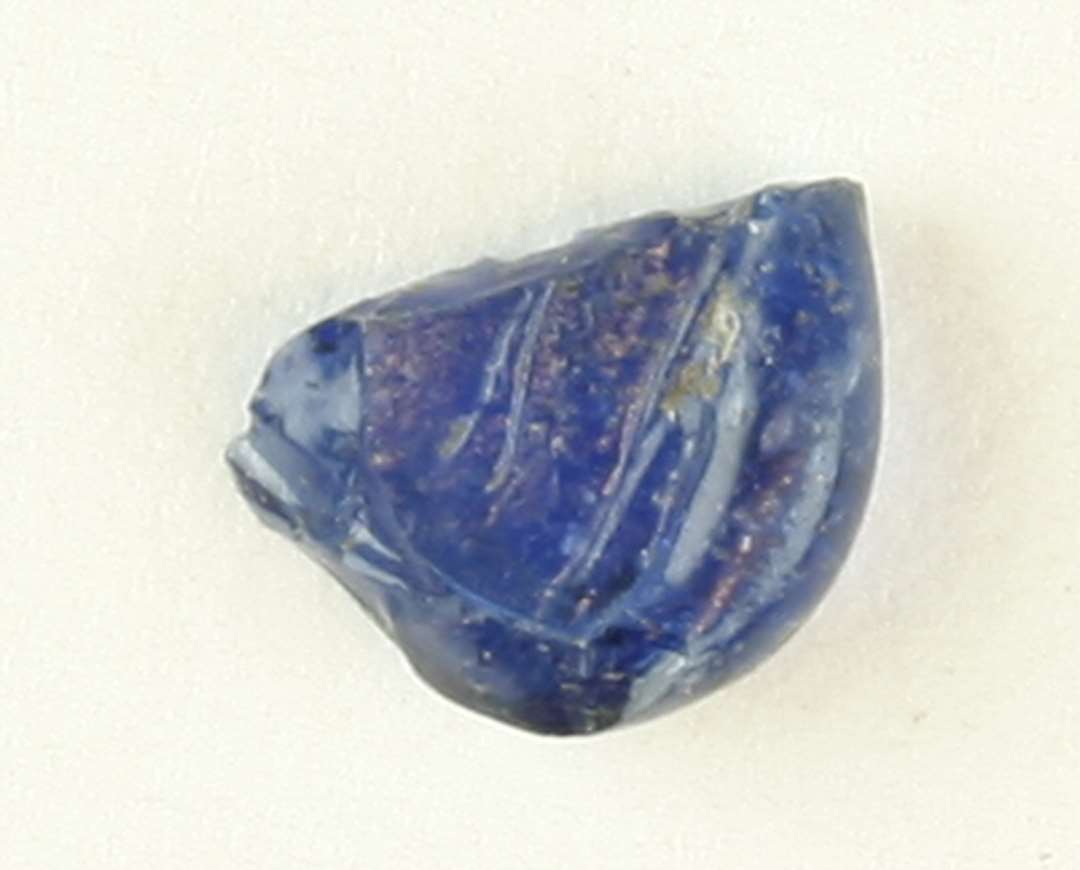 1 fragmentstump af smeltet gennemsigtigt blåligt glas med aftryk af tangbid på begge fladsider.