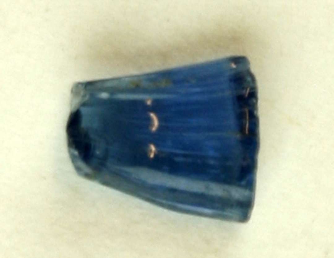 1 afbrudt stykke gennemsigtigt blåligt glas af flad, spids udtrukket form.