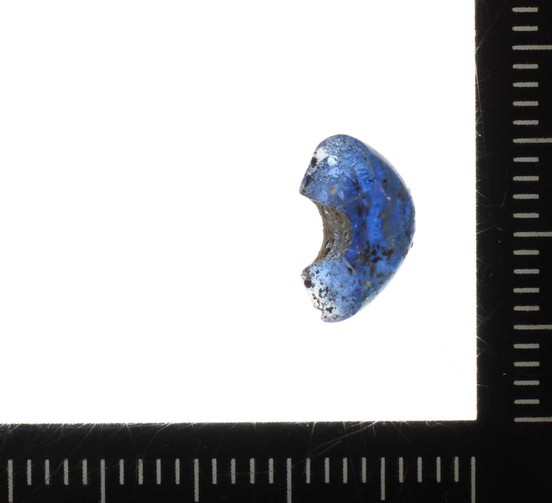 ½ perle af afrundet ringform og af gennemsigtig blålig glasmasse. 10 mm
