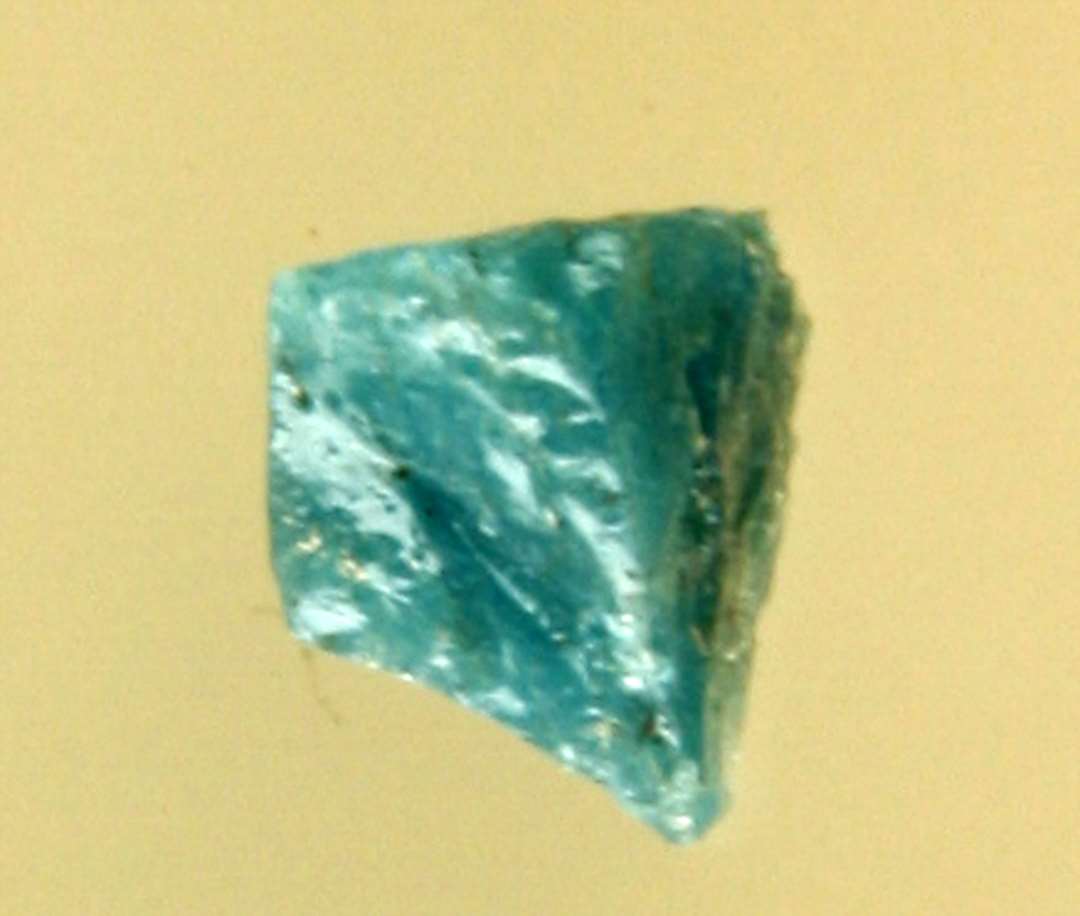 1 fragmenteret mosaikstift af blålig ugennemsigtig glasmasse.