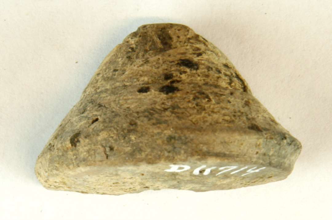 ½ tenvægt af gråbrunlig, brændt lermasse. Stykket har konisk form med svagt hvælvet underside, affaset fodrand og omkringløbende drejefure på skråfladen. Diam: 4,3 cm. H: 2,7 cm.