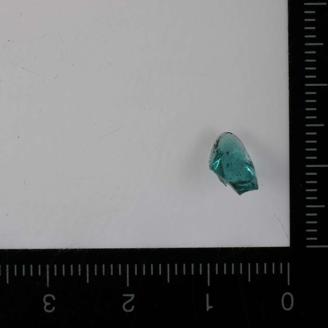 1 brudstykke af perle af grønligt glas. ST. L: 0,9 cm.