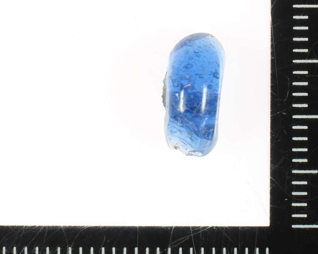 ½ perle af afrundet ringform og af blåligt gennemsigtigt glas. 11 mm.