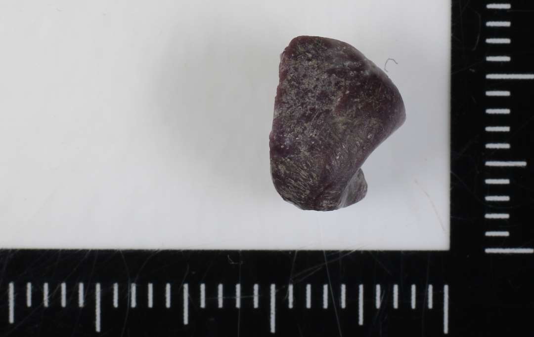 1 fragment af delvis smeltet cylinderformet perle af lilla ugennemsigtig glasmasse. 10 mm.