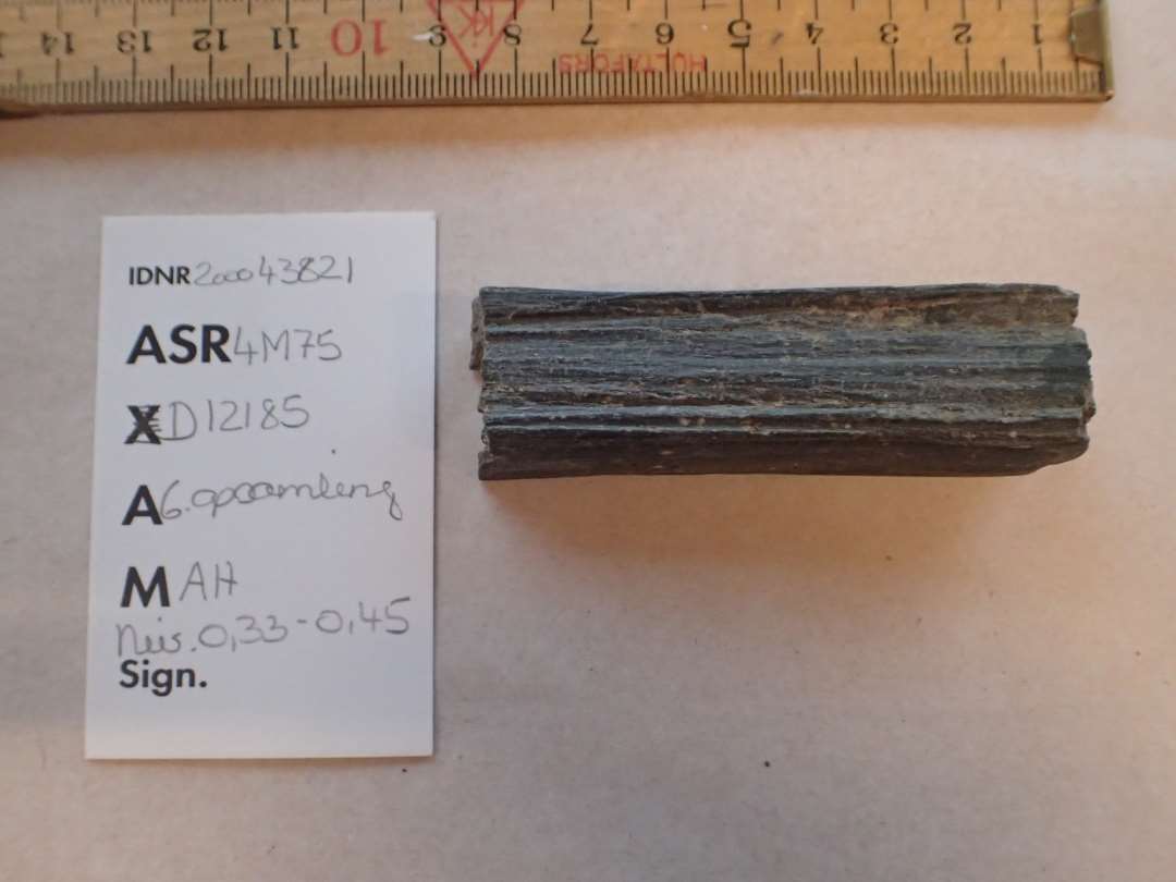 1 fragment af stangformet hvæssesten af grålig skifer overbrudt på midten L: 7,8 cm.