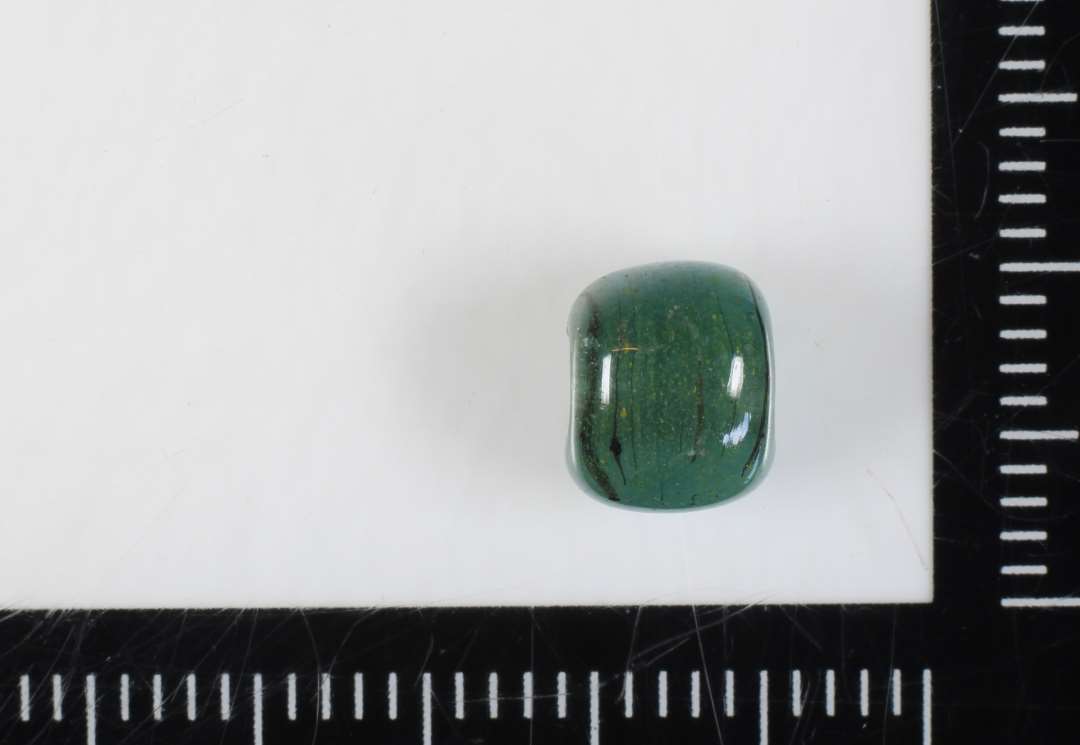 ½ perle af cylinderform med afrundede endekanter af grønligt, delvis gennemsigtigt glas. 6 mm.