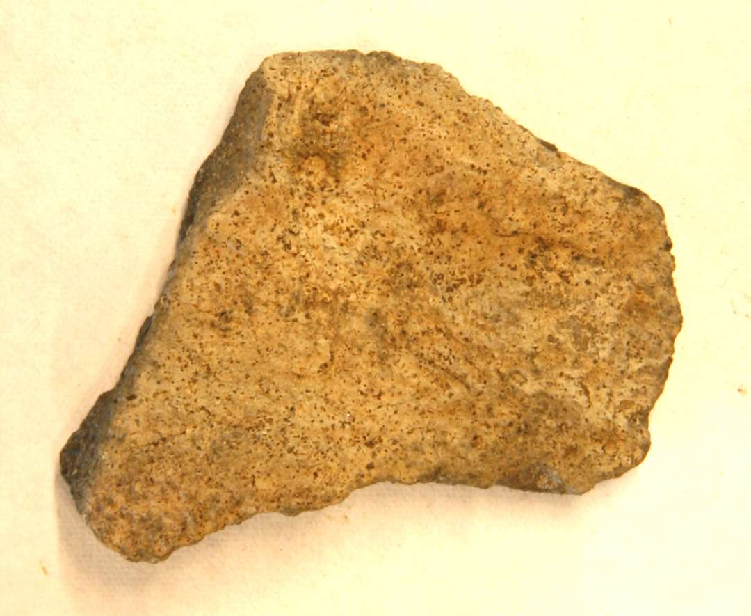 1 fragment af overfladen på discosformet vævevægt af brungrå, brændt lermasse. Største mål: 4,5 cm.