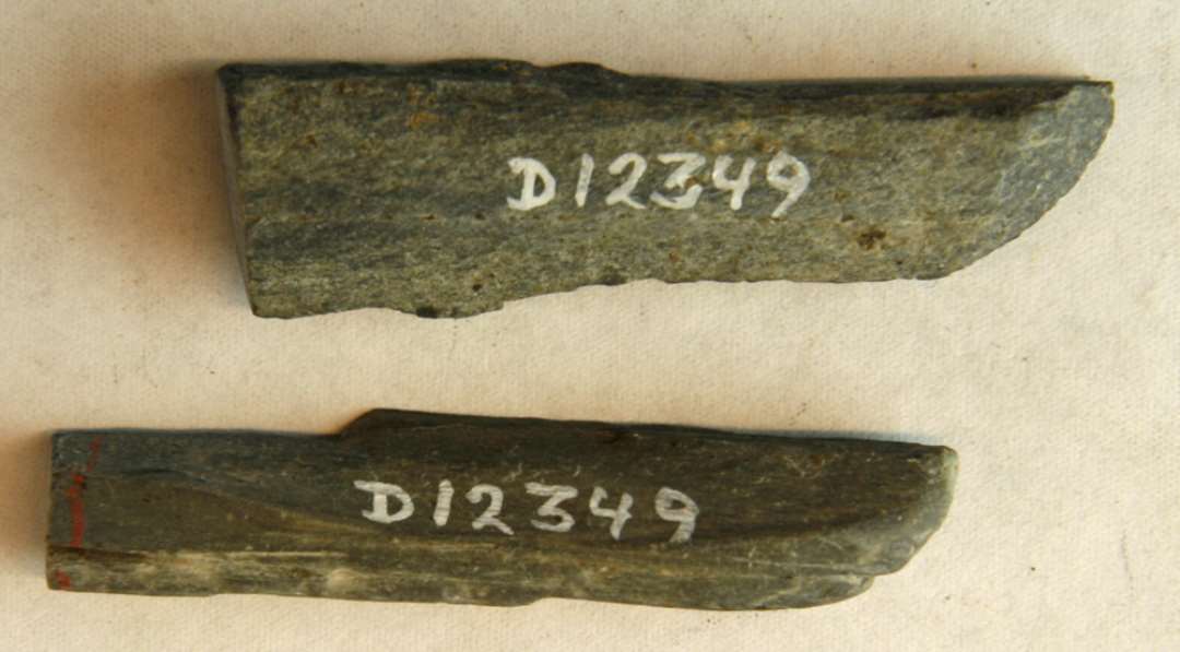 2 aflange fragmentsplinter med slibespor fra stangformede hvæssesten af grålig skifer. L: ca. 6,7 cm.