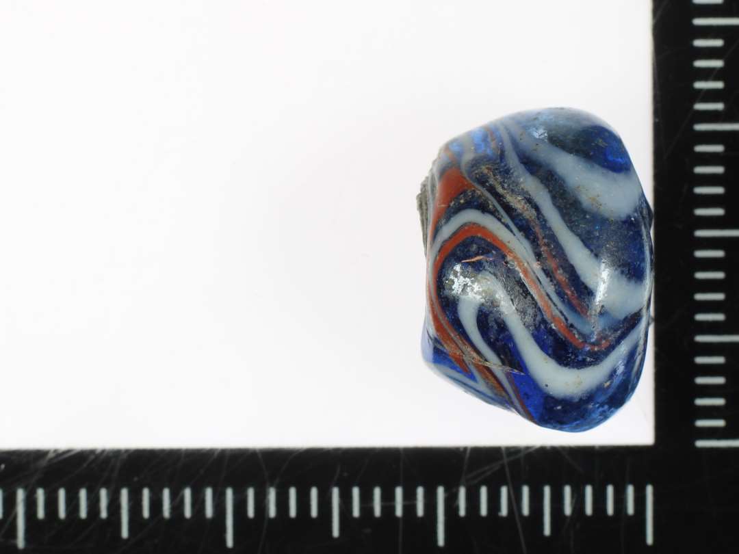 ½ konisk perle af blåt glas med broget marmorering på ydersiden. St. H: 1 cm.