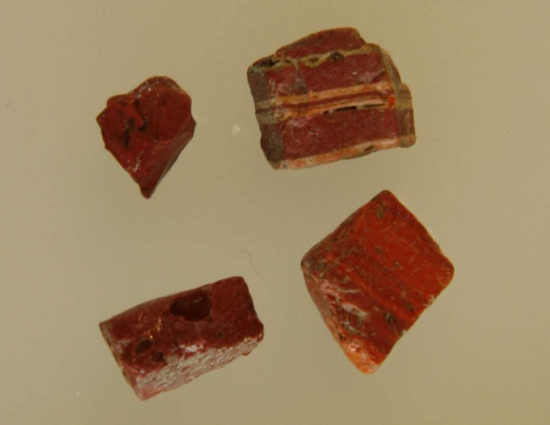 4 klumper af rødbrunt glas med marmorering.