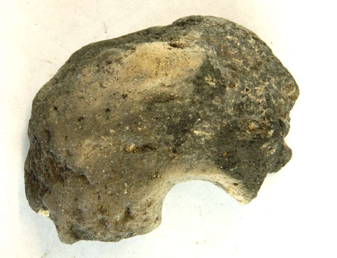 1 fragment af vævevægt af brændt ler. Midthul og ca. 1/3 bevaret. Mål: 7 cm.