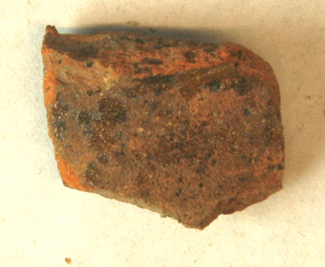 1 halsskår fra kar med udadbøjet rand af rødbrændt lergods med pletter af klar blyglasur på yder- og indersiden. Gr. 1.