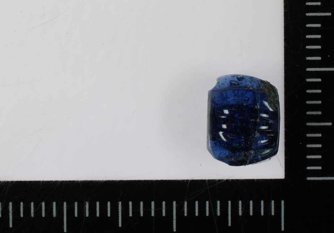 ½ perle af gennemsigtigt blåligt glas og af fladtrykt kugleform med tætte lodrette melonriller på ydersiden. 8 mm.