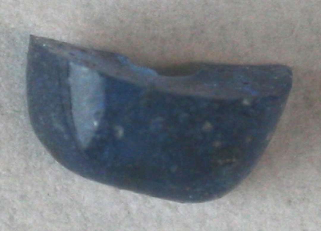 1 endefragment af cylinderformet (?) perle af blåligt, gennemsigtigt glas. 8 mm.