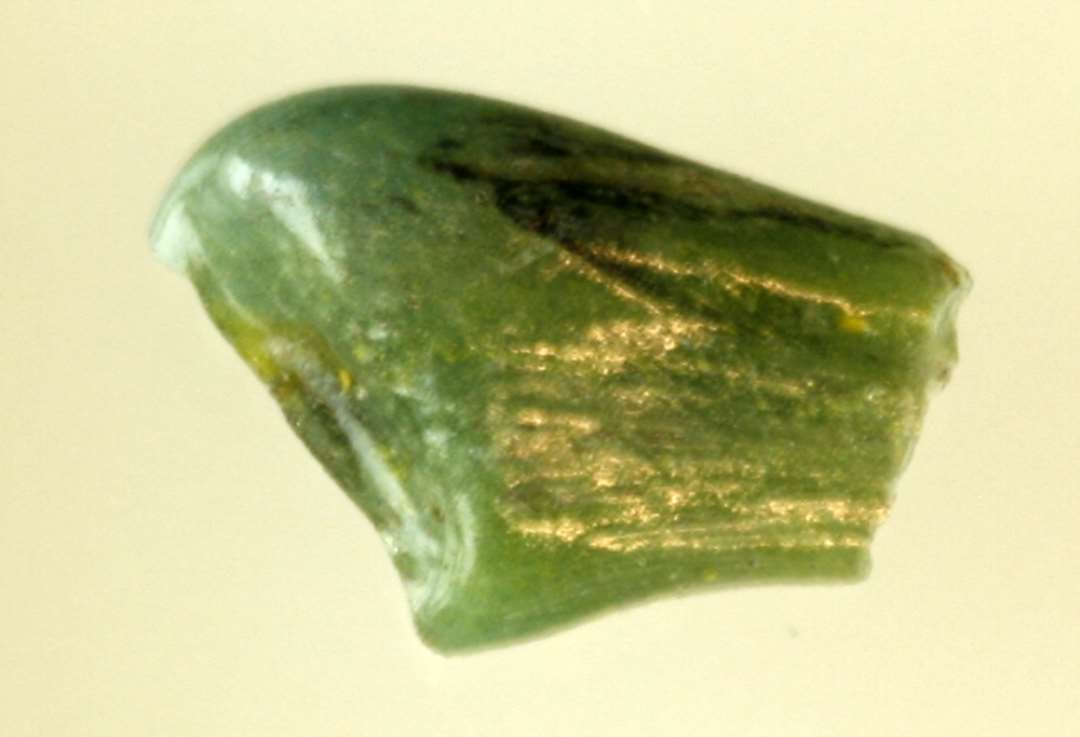 1 stump smeltet, gennemsigtigt grønblåligt glas af uregelmæssig bred flad form overbrudt i begge ender.