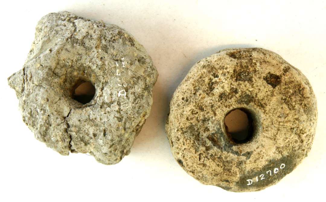 2 let fragmenterede, discosformede vævevægte af brungrå brændt lermasse. Diam: 7,6 - 8,3 cm. og 8,6 - 9,0 cm.