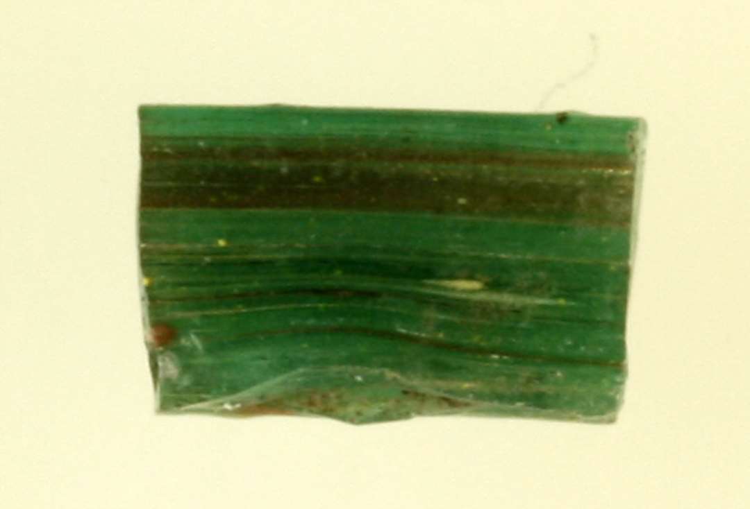 1 fragment af bændelformet glastråd af grønlig delvis gennemsigtig glasmasse.