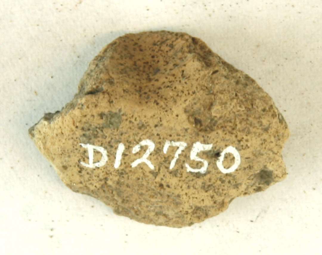 1 ubetydeligt fragment fra partiet omkring ophængningshullet på discosformet vævevægt af brændt ler. Mål: 3 cm.