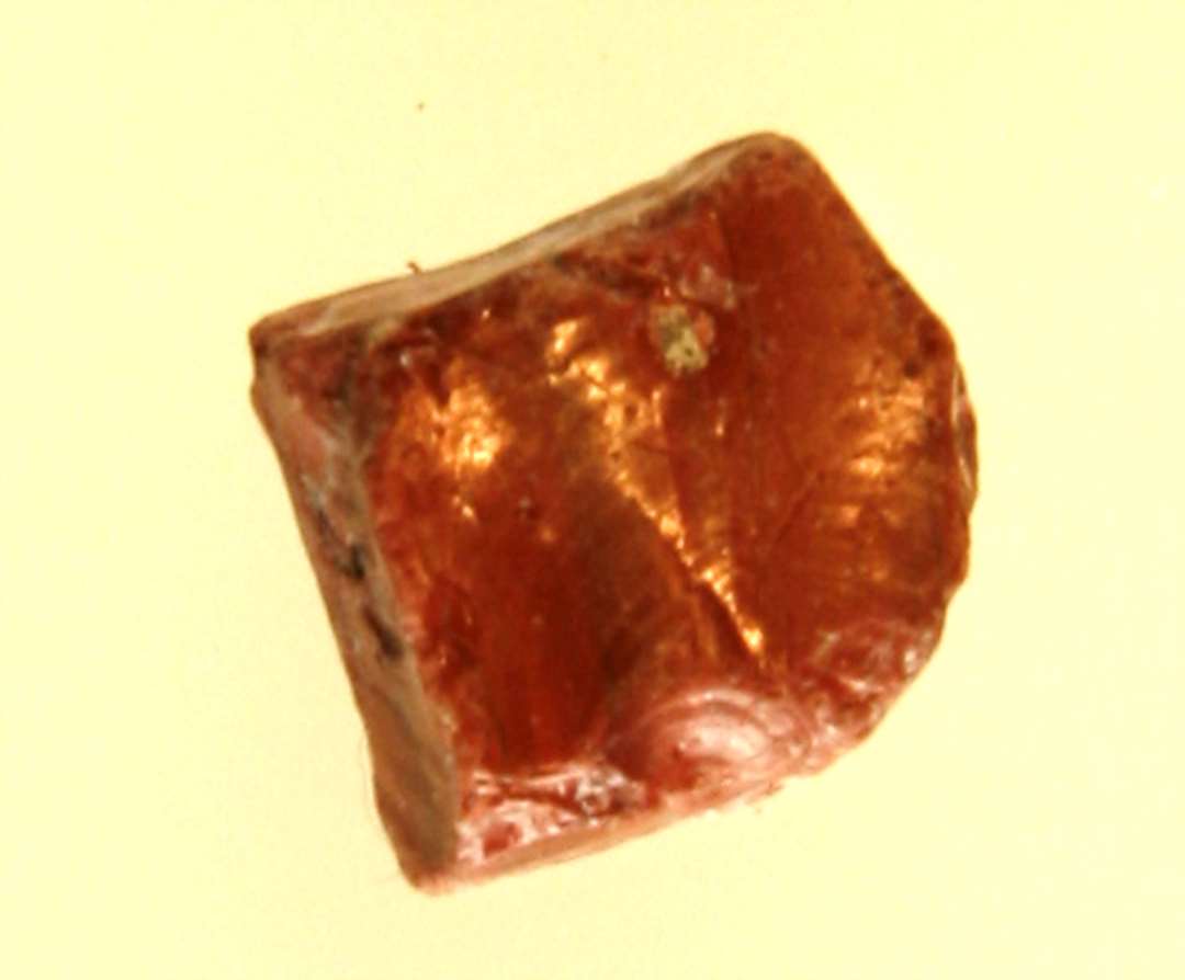 1 mosaikstift (råglasstump) af rødbrunlig ugennemsigtig glasmasse.