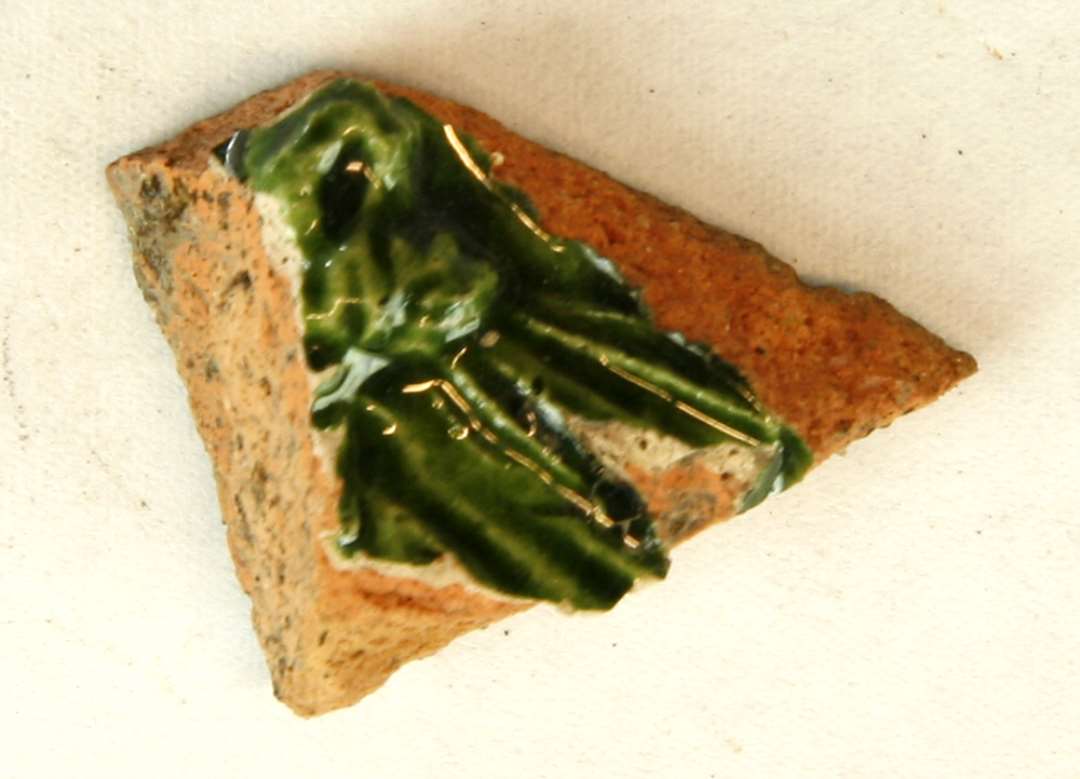 1 fragmentstump af grønglaseret kakkel. Største mål: 3 cm.