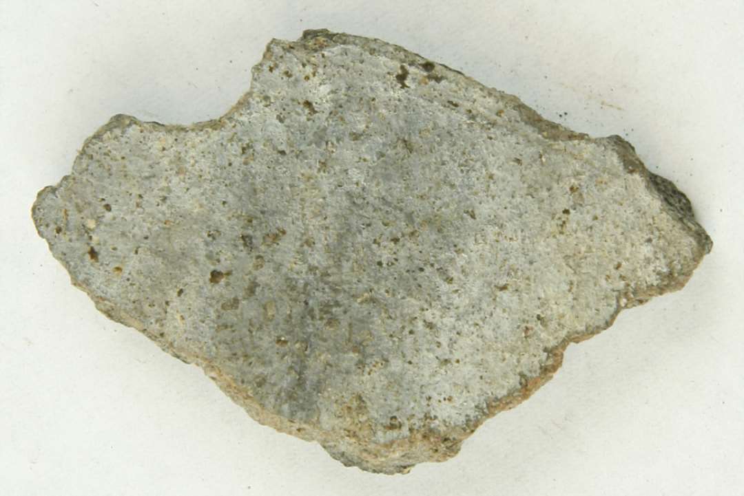 1 sideskår af gråbrændt, magret lergods fra kar med spor af tætte omkringløbende furer på ydersiden. Gr. 9.