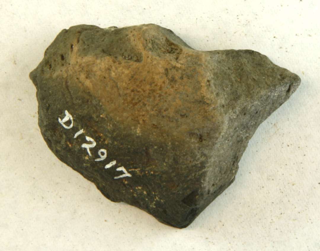 1 fragment fra midterpartiet af discosformet vævevægt af gråbrunlig, brændt lermasse. Mål: 5,5 cm.