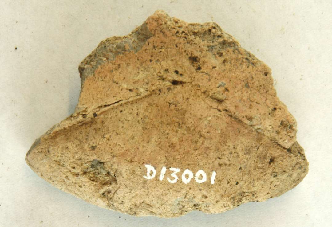 1 fragment af discosformet vævevægt af brunlig brændt lermasse. Mål: 7,5 cm.