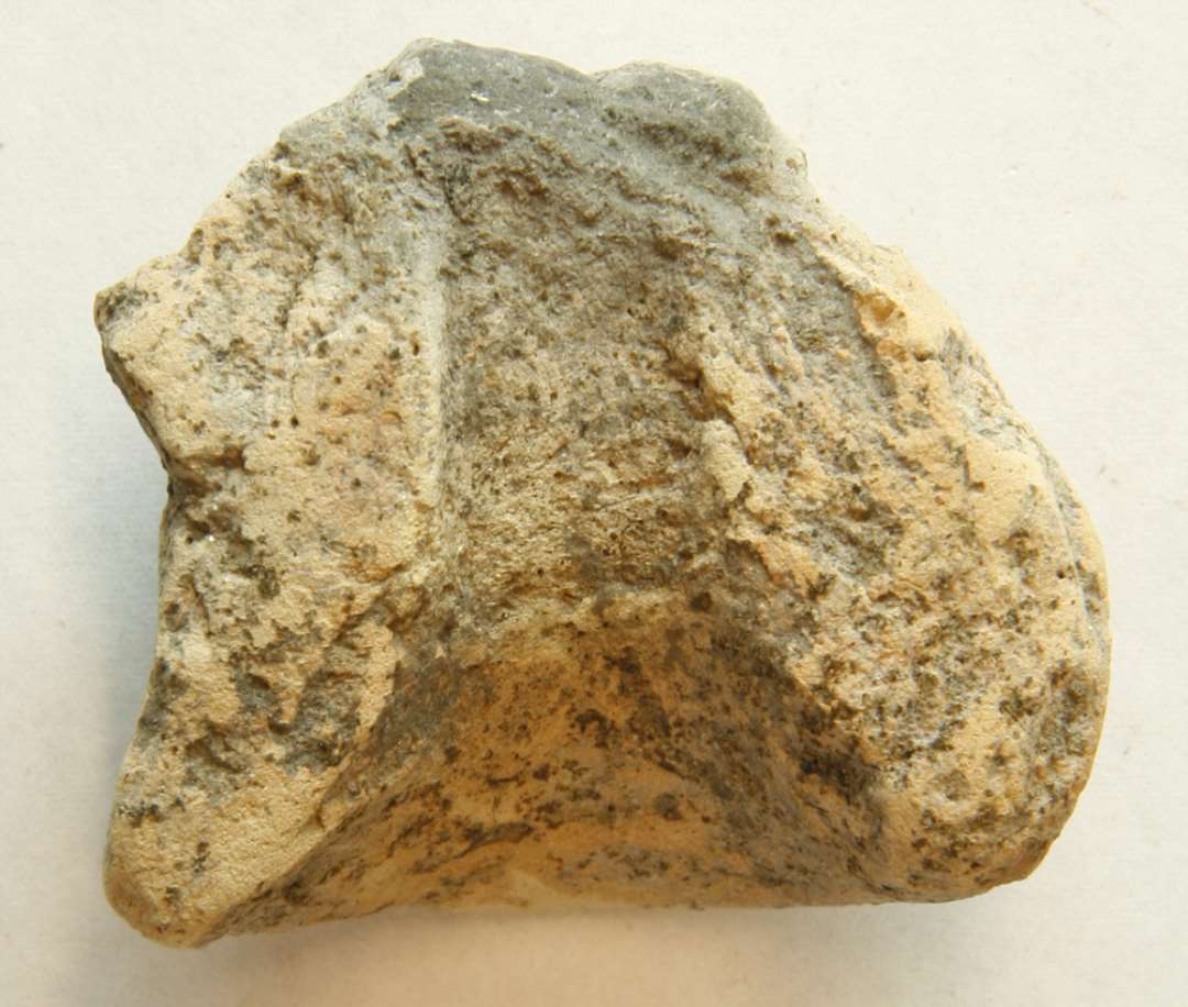 AMU 1 fragment af den tragtformede indhældningsmunding fra støbeformshalvdel af brændt ler. Mål: 4,6 x 5,1 cm. Tyk: 2,7 cm.