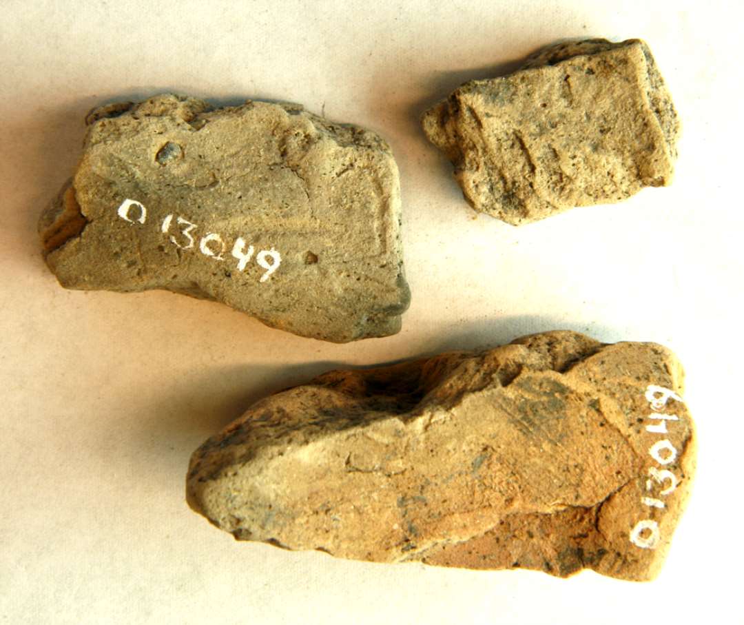 AMY 3 fragmenter af støbeforme af brændt ler, det ene fra den tragtformede indhældningsmunding. Mål: 4,4 x 2,5 x 2,0 cm. og 3,0 x 2,2 x 0,9 cm. 