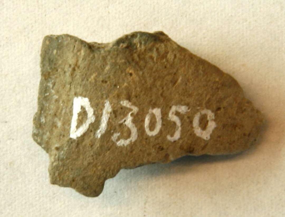 AMZ 1 fragment af støbeform af brændt ler med spor af afglattet flade på indersiden. Mål: 2,5 x 1,7 x 1,1 cm.