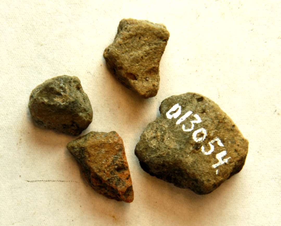 ANA 5 fragmenter af støbeform af brændt ler, det ene et randfragment fra støbeformshalvdel til skålformet spænde med ornamentspor på indersiden, de øvrige stykker er ubestemmelige gnallinger. Mål på randfragment: 2,9 x 2,4 x 1,55 cm. 1 stk. sammenlimet med D10596.
