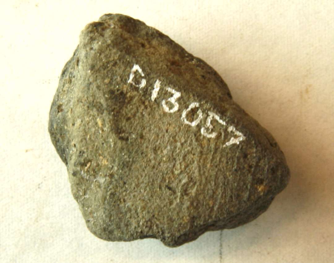 1 fragment af støbeformshalvdel af brændt ler til skålformet spænde med ornamentspor på indersiden. Mål: 3,0 x 2,6 x 1,85 cm.