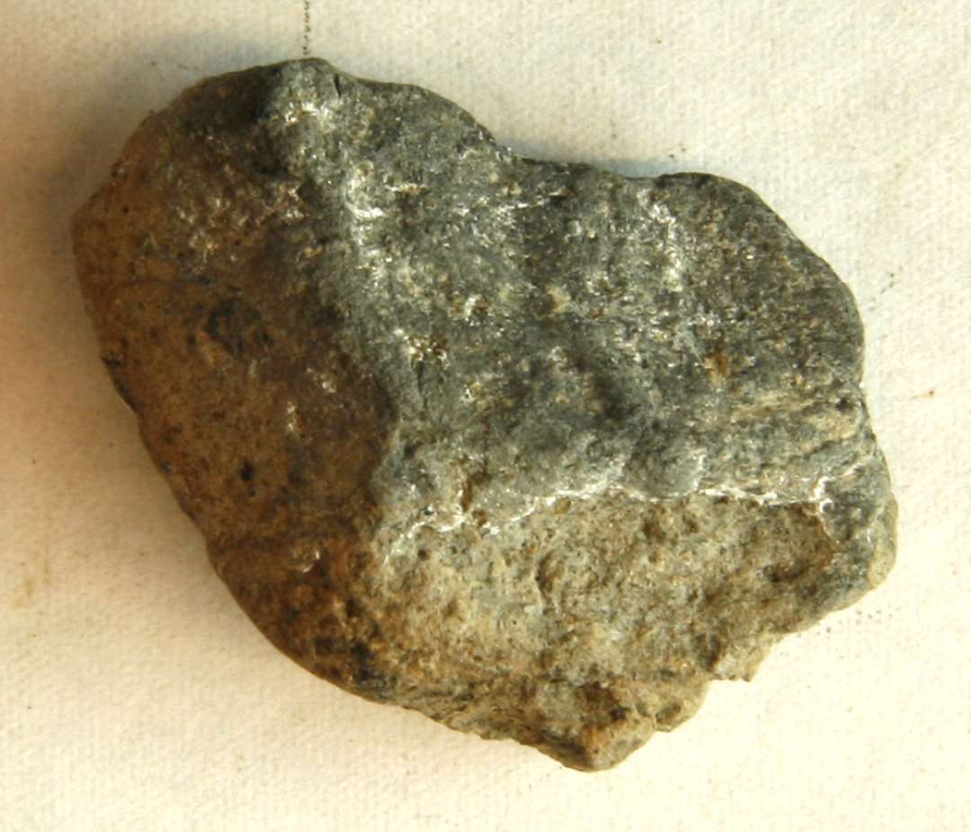 1 randfragment af støbeformshalvdel af brændt ler til skålformet spænde med ornamentspor på indersiden. Mål: 3,3 x 2,5 x 1,3 cm. 