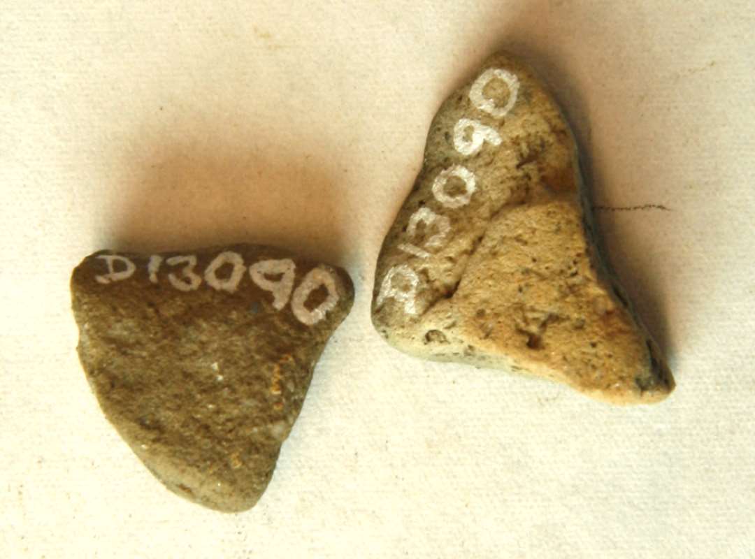 1 fragment (samlet af to stykker) af den tragtformede indhældningsmunding fra støbeformshalvdel af gråbrunligt brændt ler. Mål: 2,7 x 2,2 cm. Tyk: 1,6 cm.