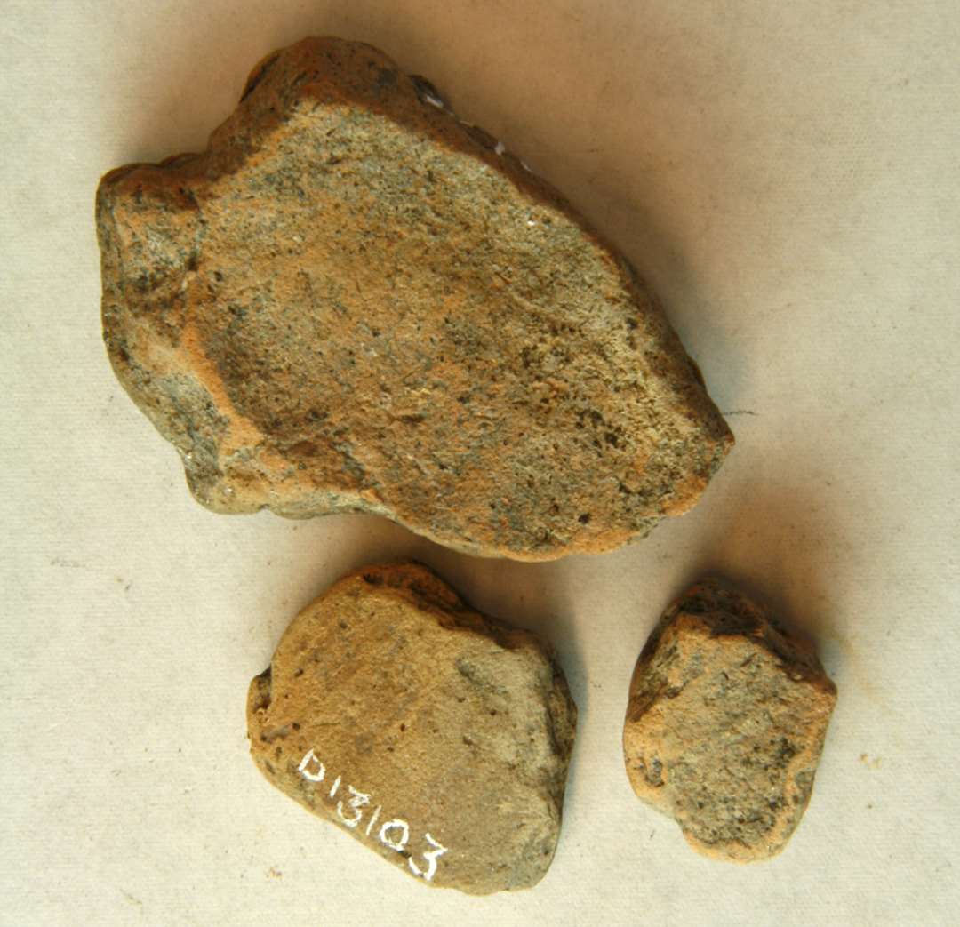 3 fragmenter af støbeforme (?) af gråbrunt fintmagret brændt ler. Fragmenterne har tykvægget, skårlignende form med let krummet vægsider glat rundet yderside, ujævn afglattet inderside. Mål: 1,9 x 1,60 cm. Tyk: 1,15 cm. 2,7 x 2,15 cm. Tyk: 1,15 cm. 4,8 x 3,70 cm. Tyk: 1,70 cm.