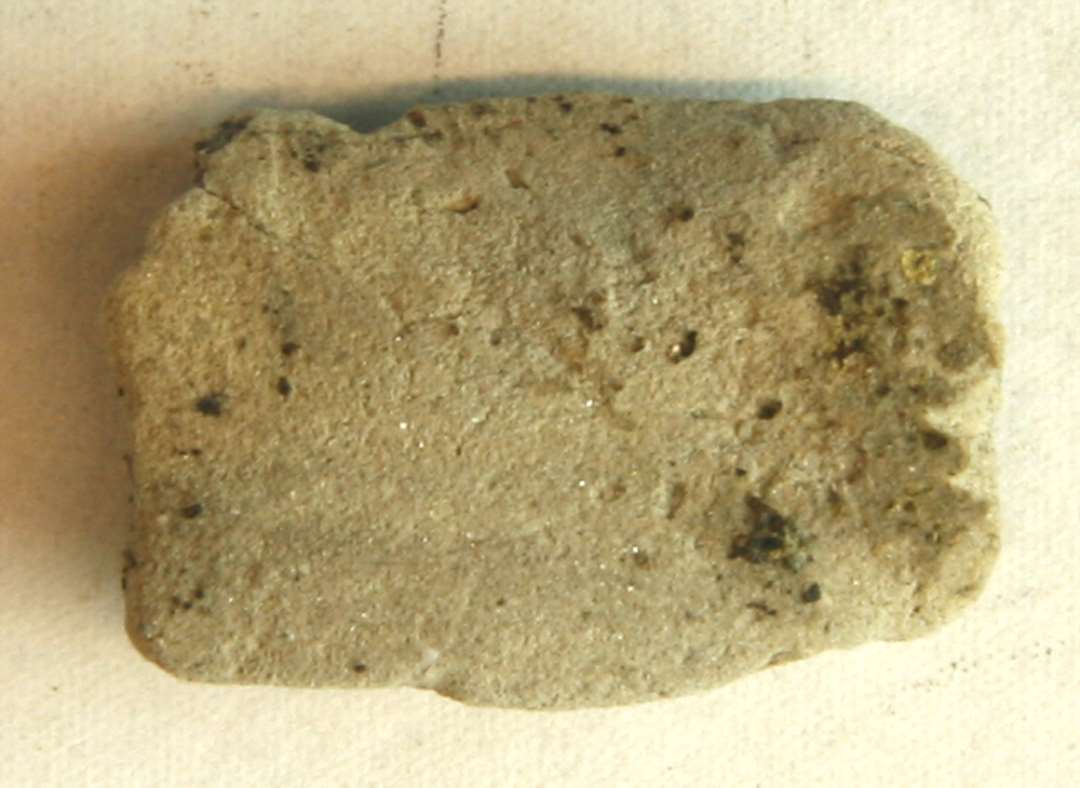 1 fragment af støbeformshalvdel af gråbrunt, fintmagret brændt ler med spor af afglattet flade på indersiden. Mål: 2,7 x 2,0 cm. Tyk: 1.15 cm.