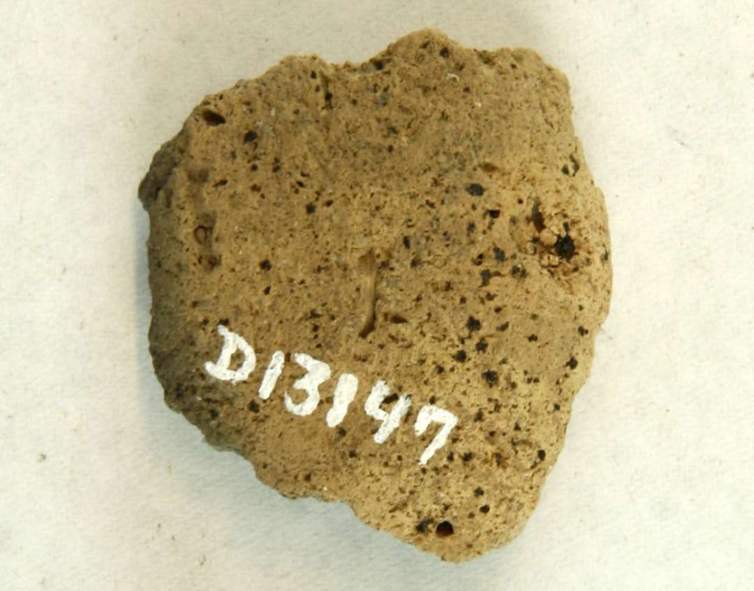 1 fragment af discosformet vævevægt af gråbrunlig, brændt lermasse. Mål: 4 cm.
