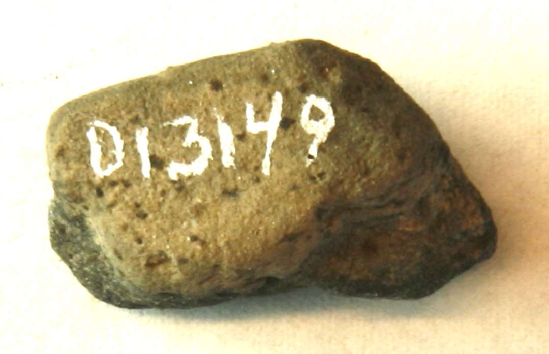 1 fragment af støbeformshalvdel af gråbrunligt fintmagret, brændt ler med spor af ornamentik på indersiden.
