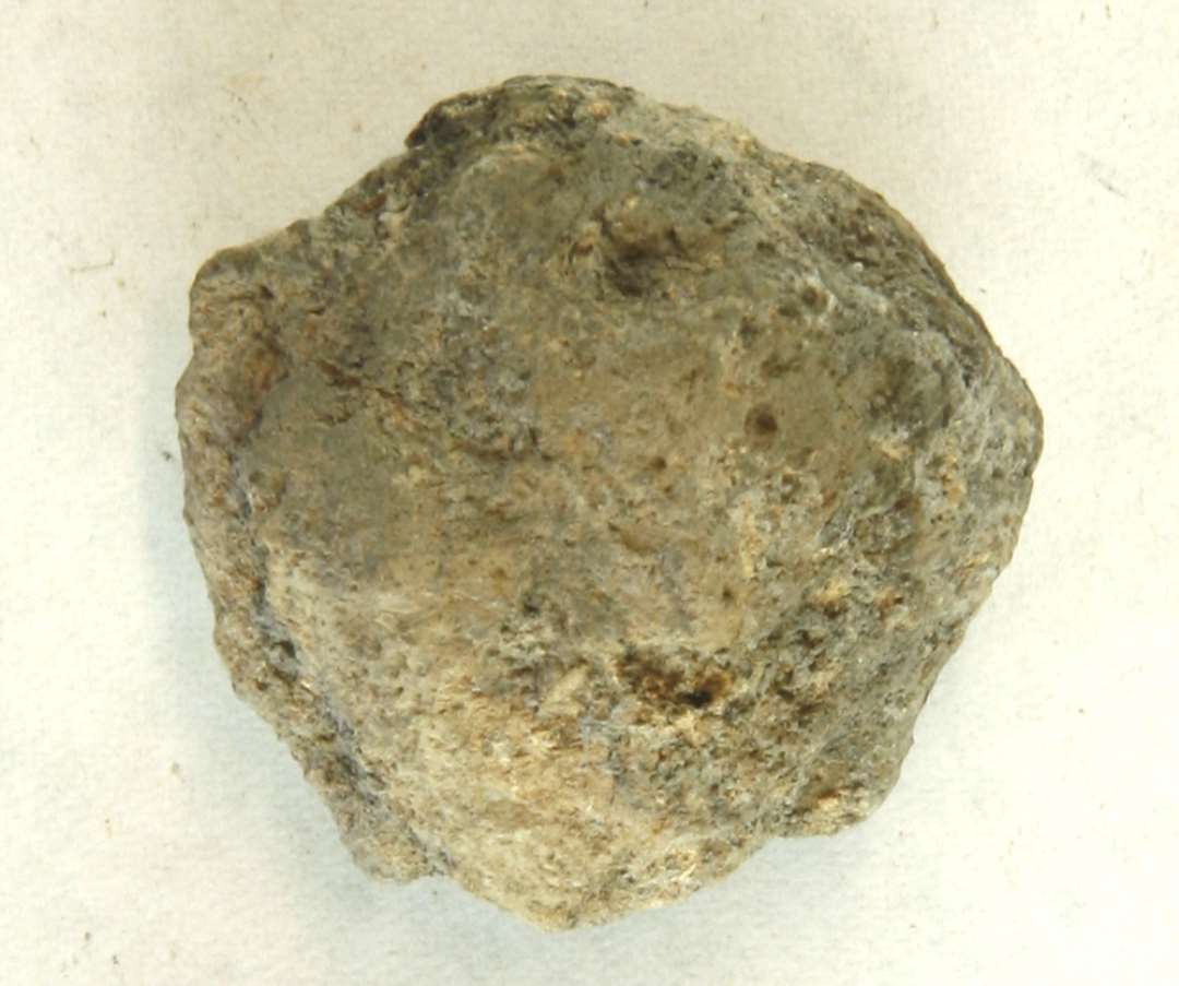 1 fragment af discosformet vævevægt af ubrændt grålig lermasse. Mål: 3,5 cm.