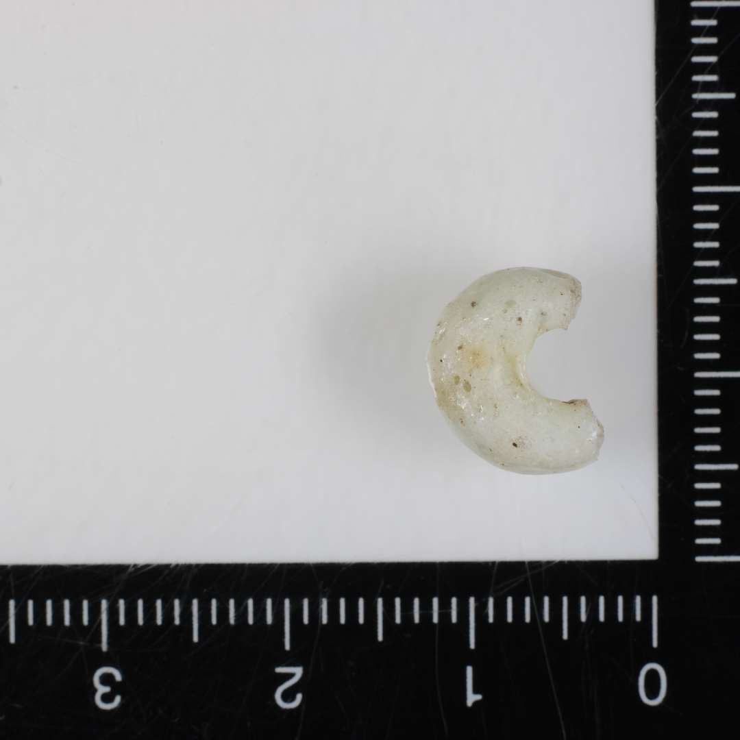 ½ perle af afrundet ringform af grålig, ugennemsigtig glasmasse spaltet på tværs. 11 mm.