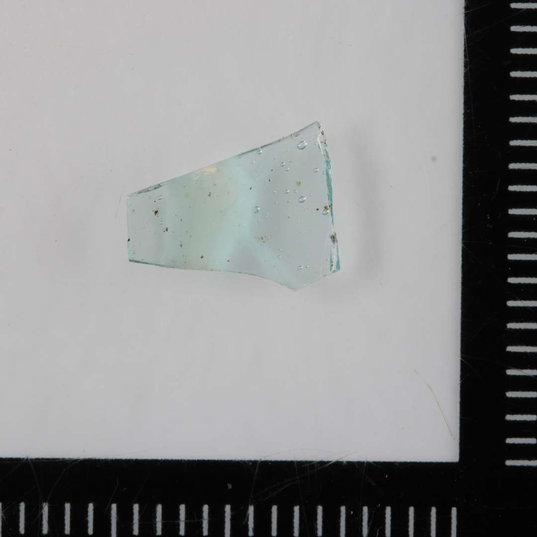 Sideskår fra kar(bæger) af klart, svagt grønligt glas med ismeltet bånd på ydersiden af hvidgrå ugennemsigtig glasmasse.