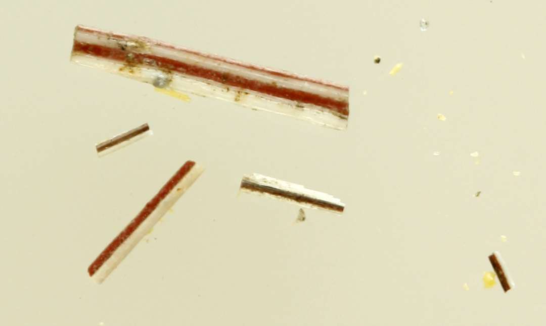 3 brudstykker af tynde, flade glastråde dannet af sammensmeltede tråde af hvidgrå og rødbrunlig ugennemsigtig glasmasse.