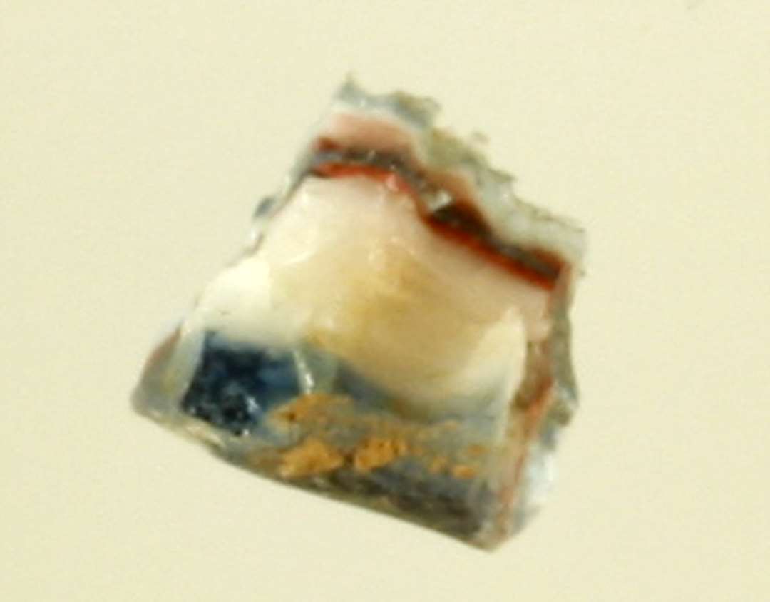 1 samling fragmenter, ialt 20 stykker, fra glasstang(-stænger) af afrundet uregelmæssig kvadratisk tværsnitsform dannet af sammensmeltede tråde af blåt gennemsigtigt og hvidt og rødbrunt ugennemsigtigt glas, således at stangens midte består af en ret tyk tråd af hlåt glas omgivet af concentriske lag af hvidt, blåt, hvidt, blåt og yderst rødbrunt glas. Det største fragments længde: 2,6 cm.