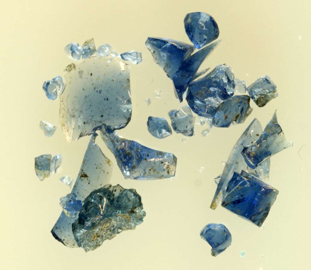 En samling råglasstumper af blålig gennemsigtig glasmasse.