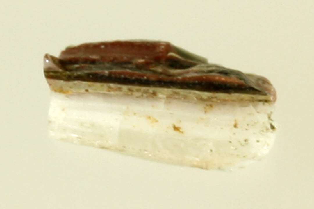 1 fragmentstump af sammensmeltet ugennemsigtig hvidgrå og rødbrunlig glasmasse. På den hvidgrå glasmasse ses spor af grønblåligt gennemsigtigt glas.
