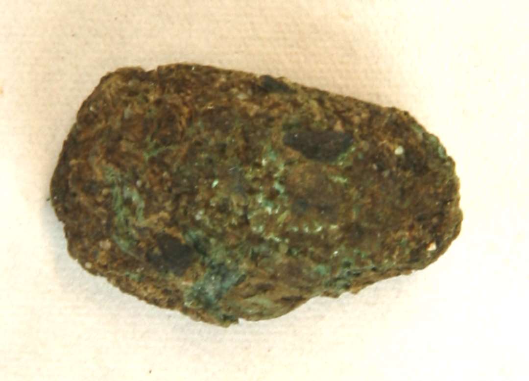1 bronzefragment af aflang form med tyk irskorpe. L: 2,0 cm.